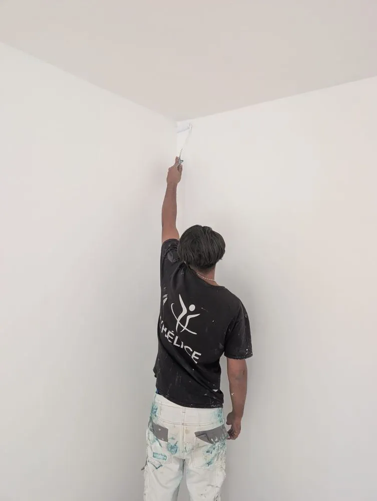 Salarié de L'Hélice peignant un mur au rouleau